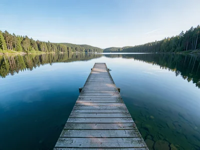 Finnish lake mirror, dead-calm reflection, a wooden dock extending into a Finnis