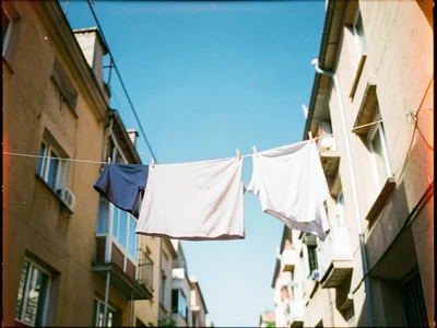 Laundry hanging on a line between apartment buildings, sheets catching wind, bri