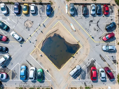 A coastal beach parking lot after a rainstorm, cars in a herringbone-angle parki