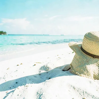 Expansive turquoise negative space, bleached whites, A straw hat resting on whit