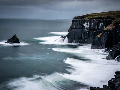 Storm waves as smooth white against black cliffs