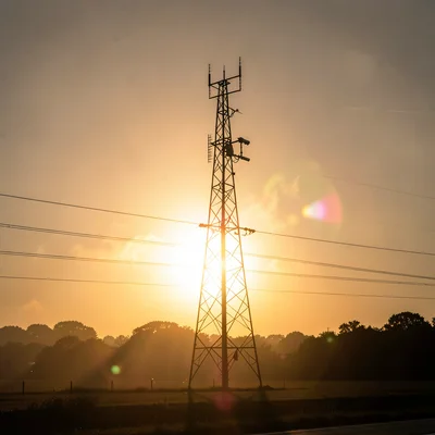 A cell phone tower at golden hour with warm atmospheric haze