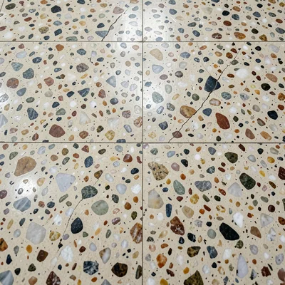 Heritage terrazzo: a worn floor showing decades of polish, some chips cracked, t