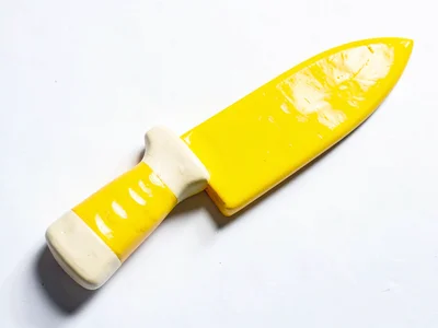 Knife-shaped chunky clay chef knife in primary yellow with stubby cream-toned bl