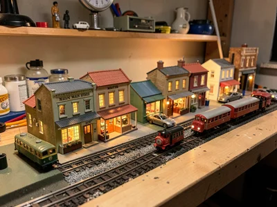Miniature Main Street scene on layout table, tiny shops with lit windows, scale 
