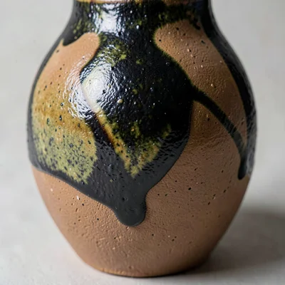 Macro close-up of a tenmoku glaze surface — brown pooling into near-black