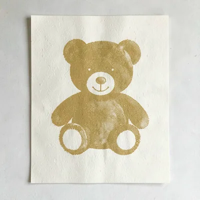 Riso poster motif of a halftone teddy bear silhouette in mustard yellow on warm