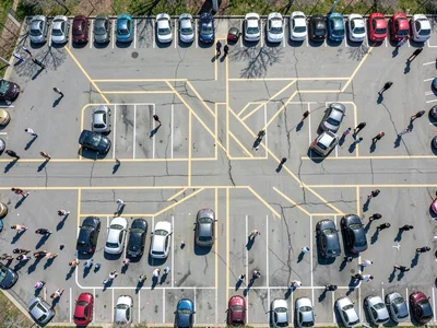 School parking lot during event, cars creating abstract pattern