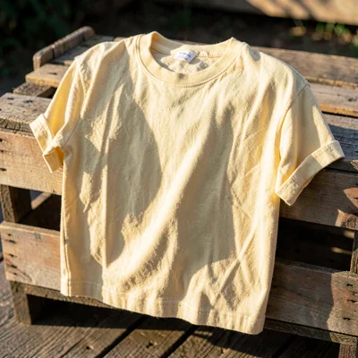 Warm garment portrait of a heavy cotton skate tee in faded butter yellow, draped