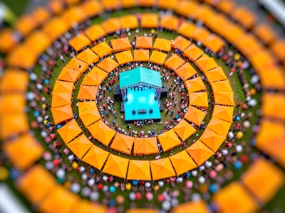 Aerial tilt-shift miniature of a music festival from drone height, saturated tan