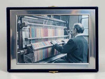 A textile loom with thousands of colored threads creating a half-finished tapest
