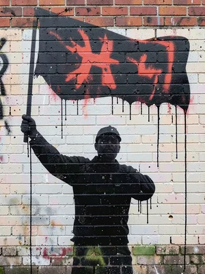 Worker raising a flag silhouette, single spray-colour on brick, paint drips trai