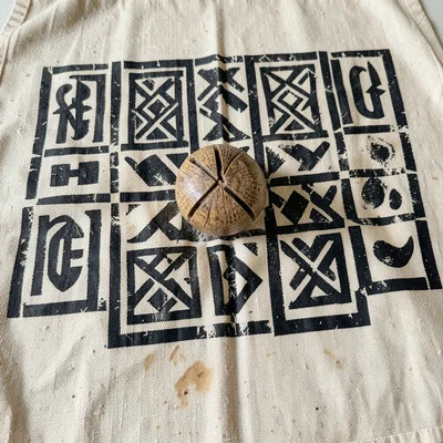 Adinkra cloth being stamped — calabash carved stamp pressed in black dye on natu