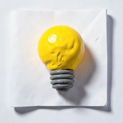 Glowing chunky clay light bulb in primary yellow with stubby threaded base and o