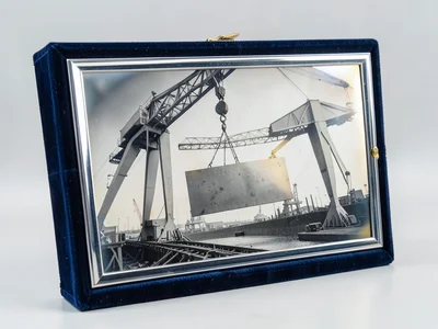 The gantry of a bridge crane in a shipyard with a steel plate suspended from ele