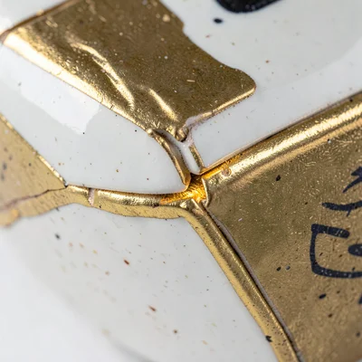 Close-up of repair junction — gold meeting white glaze, slight raised lip of lac