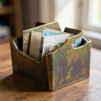 Detail of an oxidized brass postcard rack with cards tucked into the slots