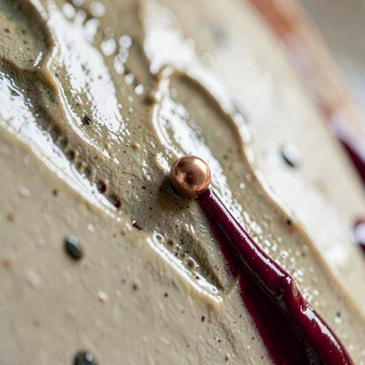Razor-tight focus on copper-red bead sliding down a porcelain wall, glossy ruby
