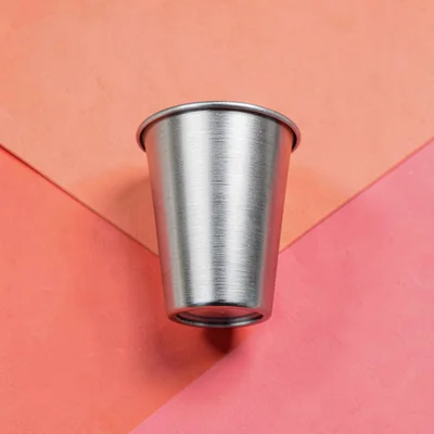 single brushed-steel laundry-detergent dispenser cup top-down on a saturated cor