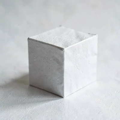 Paper macro sidebar of a tiny folded paper cube standing on edge, soft cast shad
