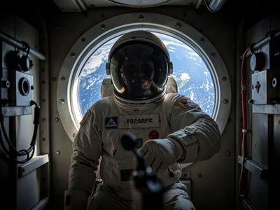 Astronaut in airlock door, Earth visible through tiny window, the ultimate thres