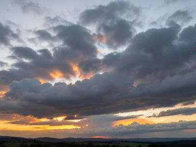 Stratocumulus layer at dawn — long low grey cloud rolls with orange gaps where s