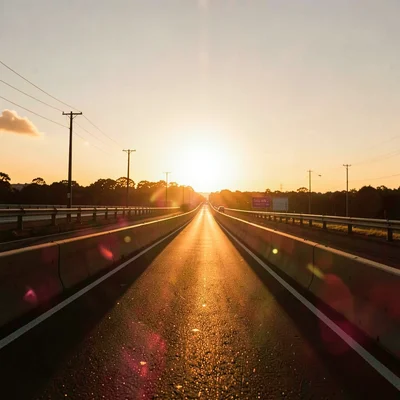 A freeway on-ramp gilded by the setting sun