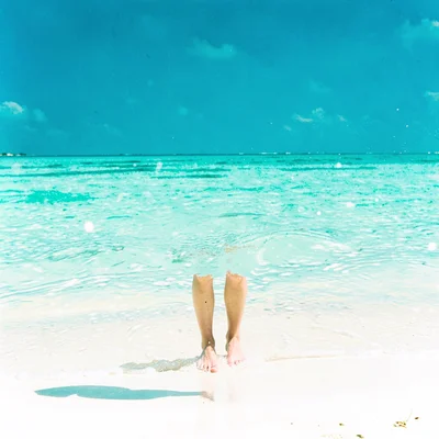Expansive turquoise negative space, bleached whites, Bare feet standing at the w