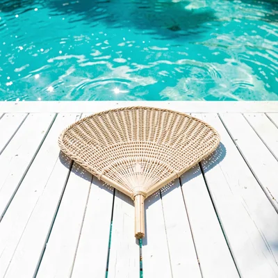 Expansive turquoise negative space, bleached whites, A woven pandanus fan laid f