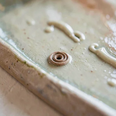Hand-built coil mark visible beneath a wash of pale shino glaze, joins softened