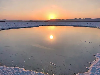 Sunrise creating glowing orb in mirror landscape