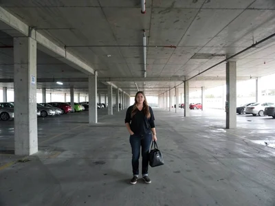 Woman in vast parking structure, concrete above below and around, her the only o