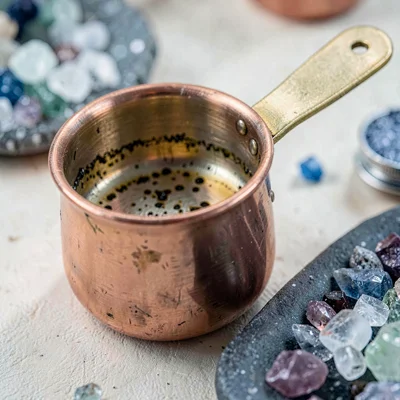 Close-up of a copper measuring beaker with bitters residue, mineral-cool palette