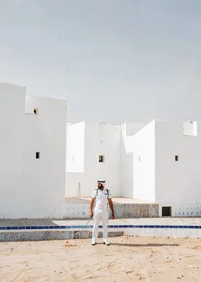 Extreme minimalist restraint of Muscat, Oman, royal guard in white, fort wall ba