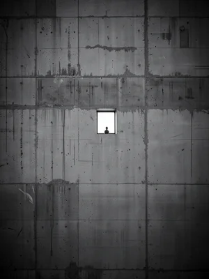 Tiny window in massive concrete wall filling entire frame