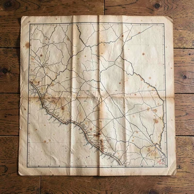 Top-down still life of a quartered map sheet with deep fold lines, foxing along