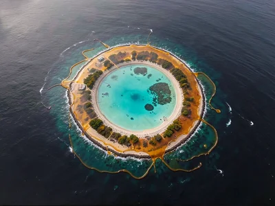 An atoll reef ring seen from high altitude with turquoise lagoon center and dark