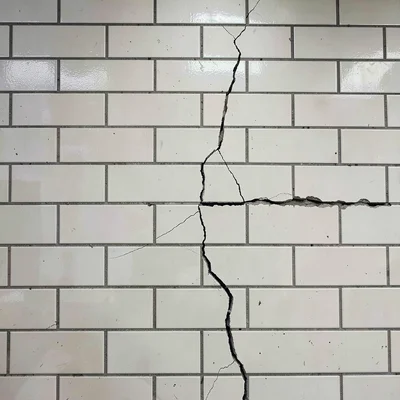 Subway tile wall with single crack breaking the pattern, perfection ruined