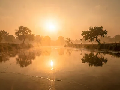 River surface reflecting amber sky through dust layer