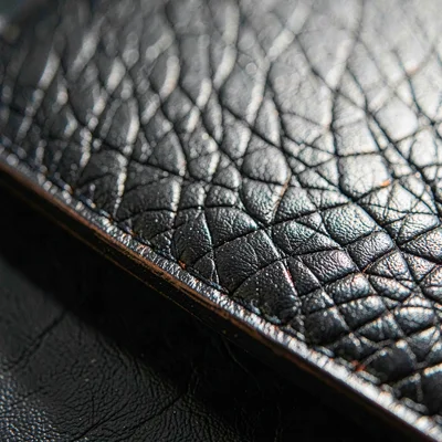 Tight macro of full-grain calfskin across a wallet edge, raking sidelight reveal