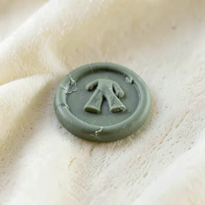 Engraved sage-green wax seal with a slumped center and fingernail dents around t