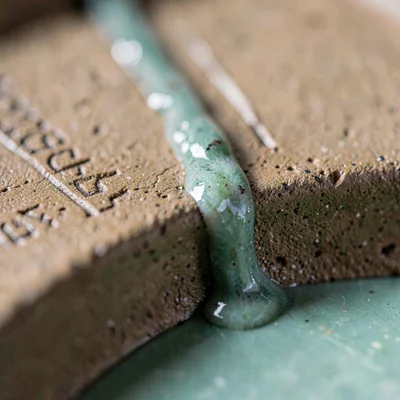 Razor-sharp ash-glaze drip running down a hand-pressed groove, jade pooling at t