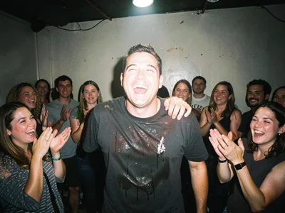 Comedian taking bow in tiny club, sweat-soaked shirt, harsh spotlight, maybe twe