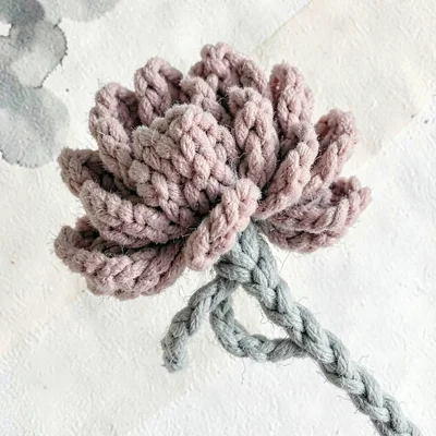 Bunched dusty-rose knit peony with layered fuzzy petals and a soft-sage knit ste