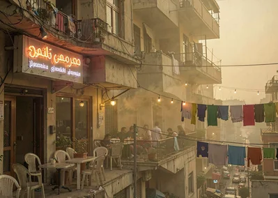 Dusty golden Cairo haze compressing apartment layers, coffee shop exterior with 