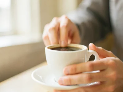 Hand reaching for coffee cup, background dissolved