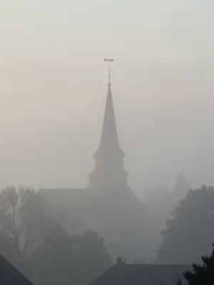 A church spire emerging from a blanket of fog, only the top 20 feet visible, a w
