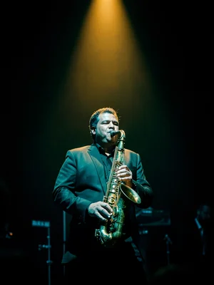 A saxophone player on a stage, a single warm amber spotlight, everything else in