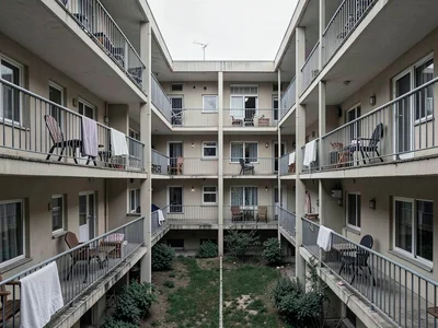Apartment complex courtyard — identical balconies, identical chairs, one with a 