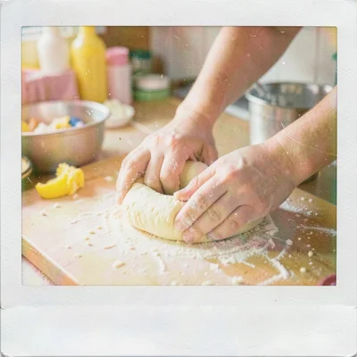 Expired Polaroid instant film photograph, Hands kneading bread dough on floured 